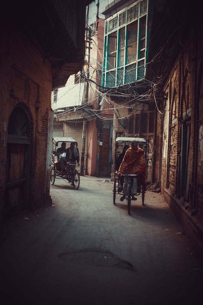 Rickshaws move through a narrow alley, showcasing urban life in India.